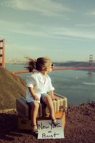 Little girl sitting on suitcase looking out onto Golden Gate Bridge